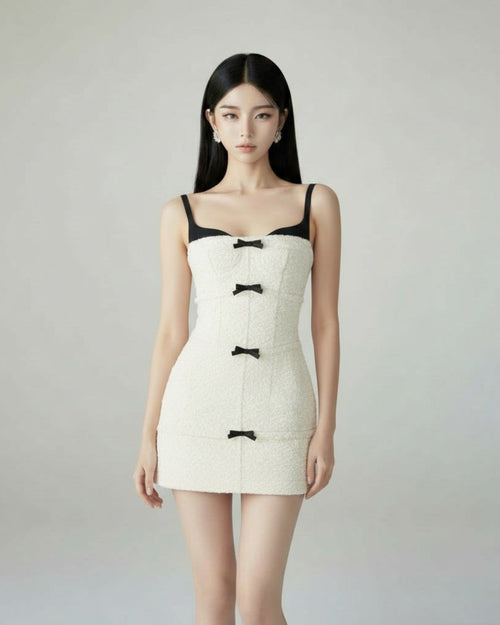 Model wearing The Heiress Dress by Seonyo – structured white tweed mini dress with black bow detailing